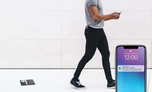 Handsome young curly man in casual outfit browsing smartphone while walking on marble passage