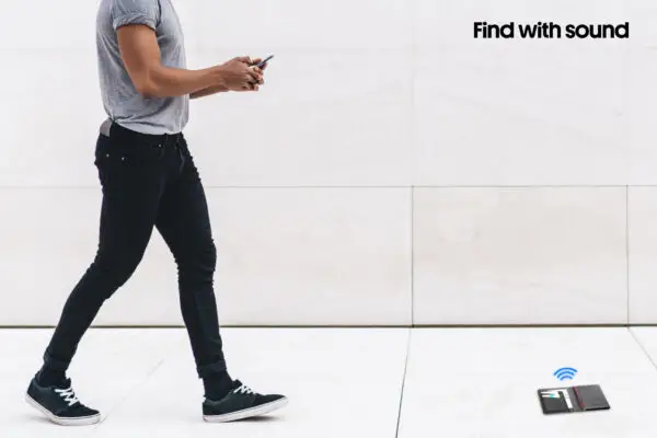 Handsome young curly man in casual outfit browsing smartphone while walking on marble passage